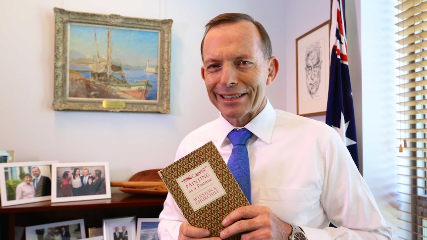 Tony Abbott holds a copy of Winston Churchill's book, Painting as a Pastime, in his office.