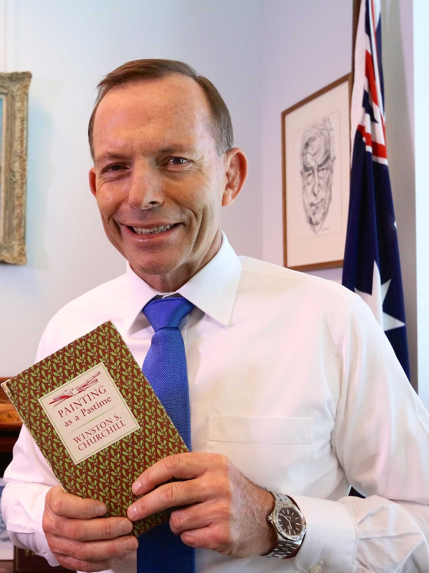 Tony Abbott holds a copy of Winston Churchill's book, Painting as a Pastime, in his office.