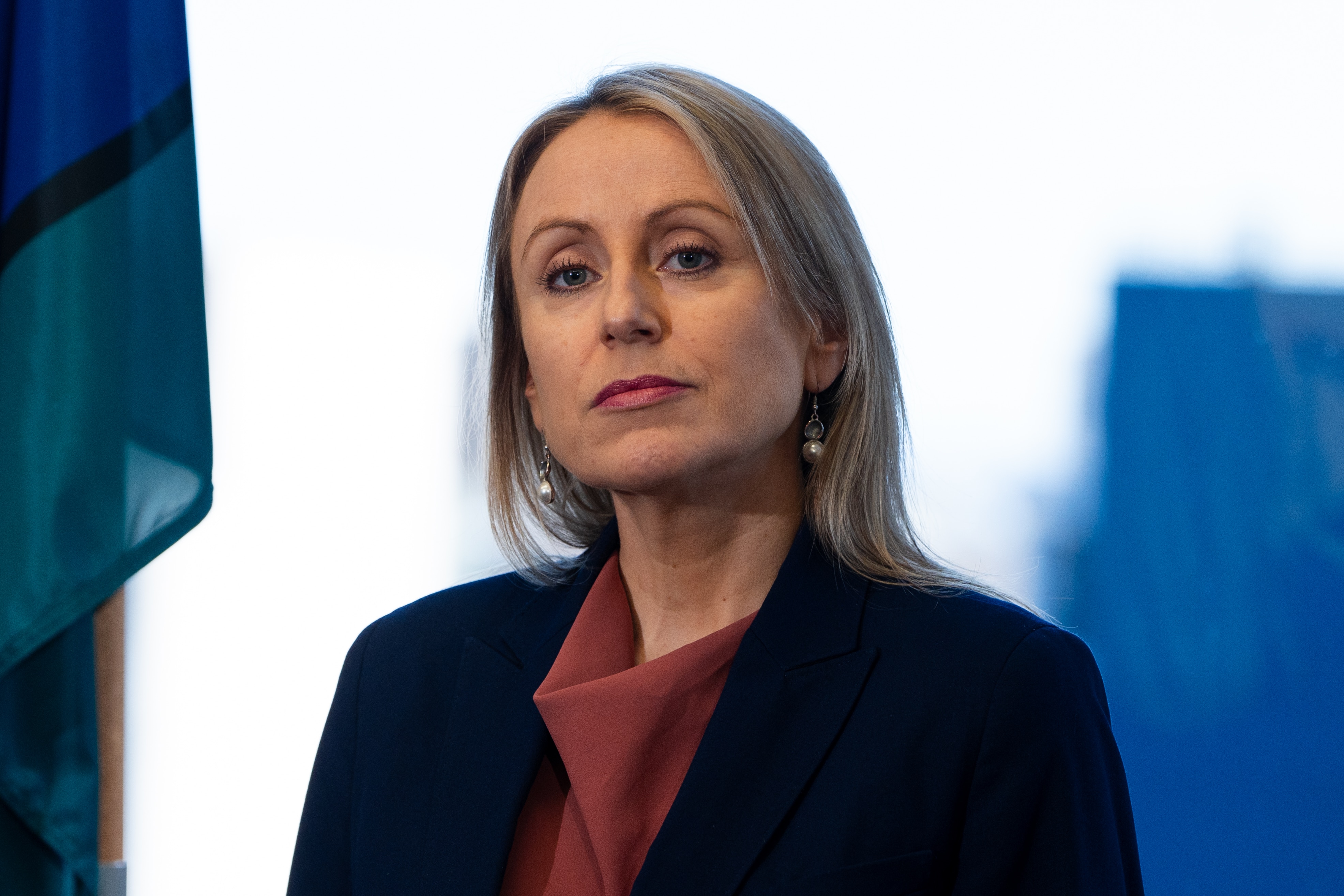 A blonde woman wearing a tailored blazer.