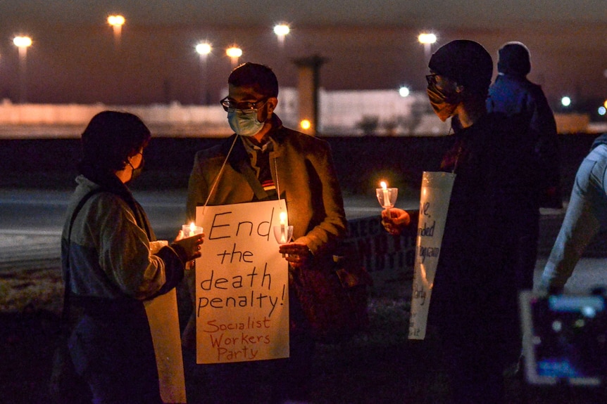 Protesters at a candlelight vigil hold up placards that read End the death penalty! Socialist Workers Party