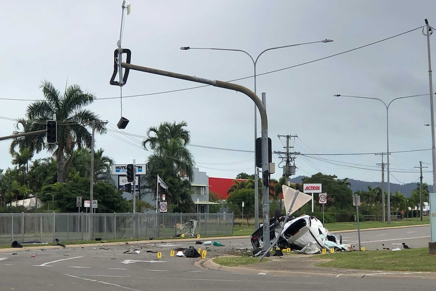 A car is wrecked against a traffic light pole, which is also badly damaged