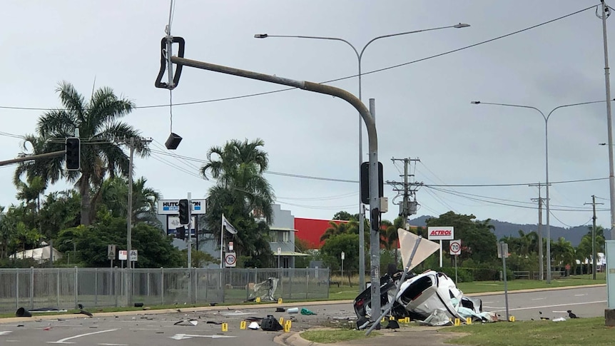 A car is wrecked against a traffic light pole, which is also badly damaged