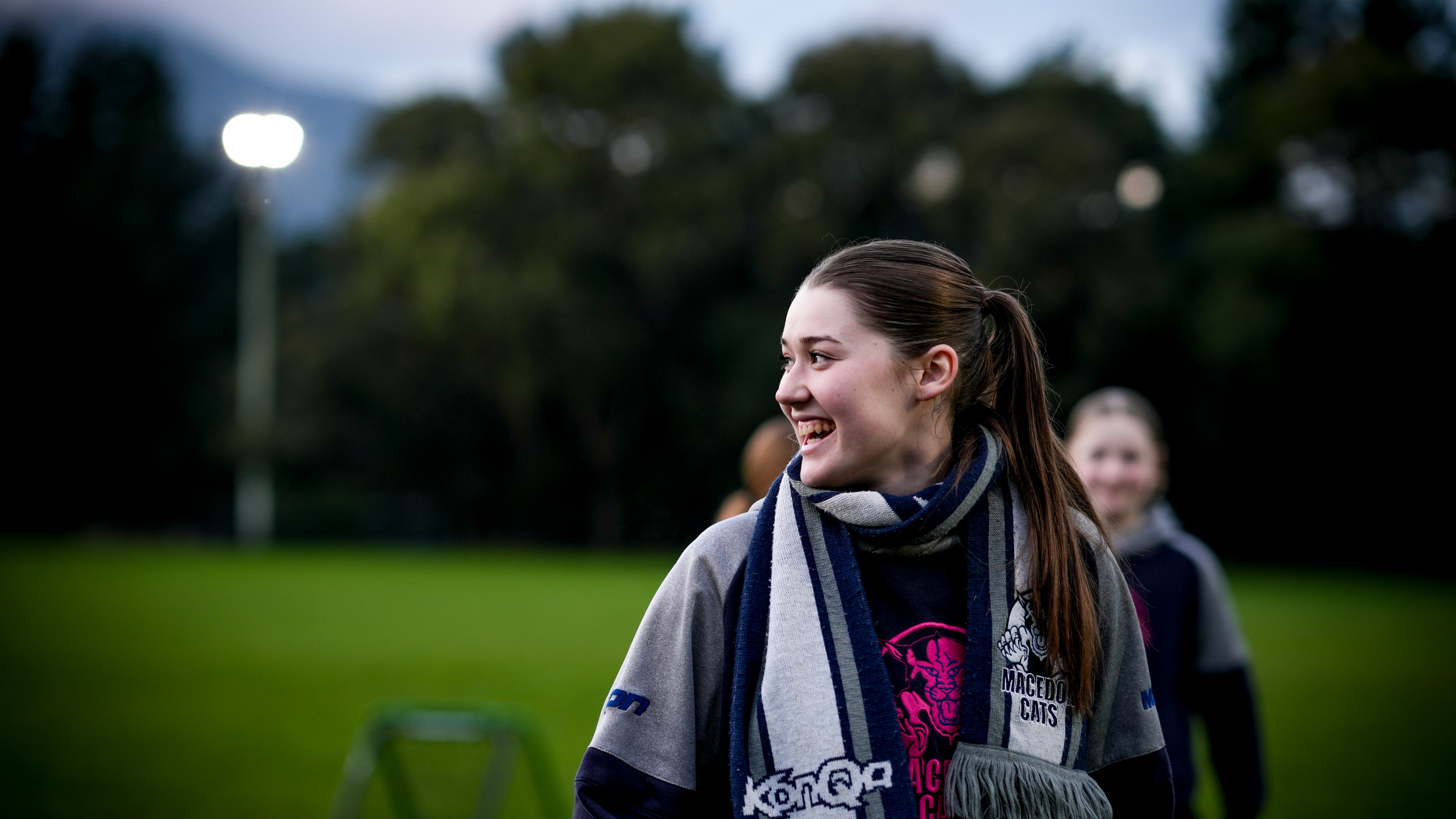 A laughing woman with a scarf around her neck, outdoors.