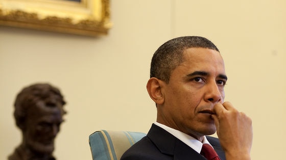 Midshot of President Obama with reflection seen in desk.