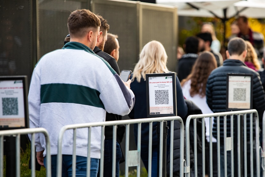 A man standing in line scanning a Safe WA QR code.