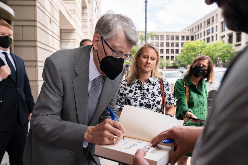 Stephen King signs a fan's book.