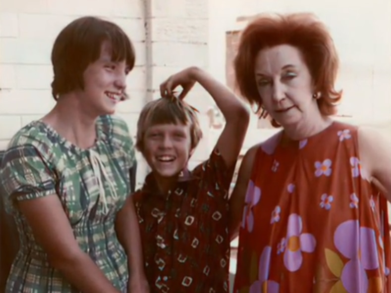 A slightly faded photograph of a teenage girl and boy with an older woman.