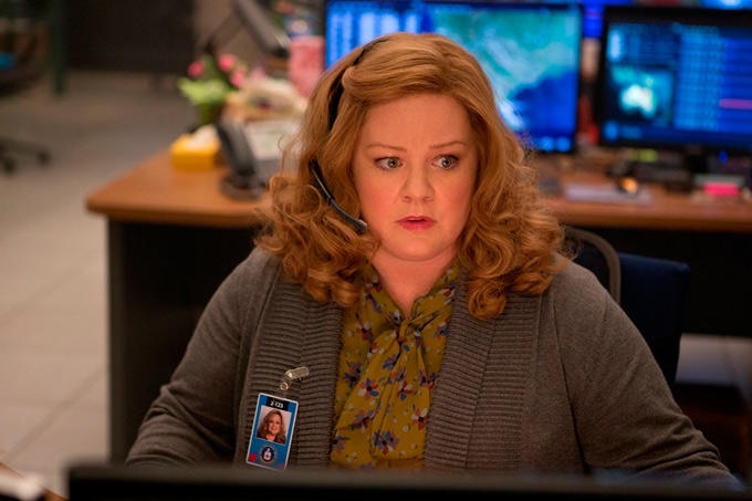 A woman sits in an office at a desk wearing a headset.