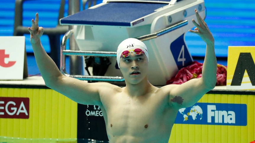 Sun Yang holds up four fingers on each hand above his head, in the swimming pool after the race.