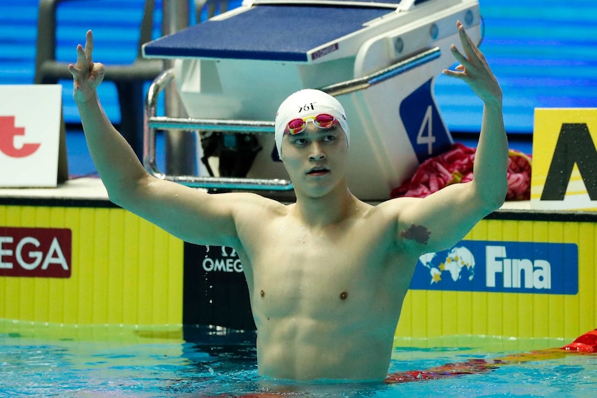 Sun Yang holds up four fingers on each hand above his head, in the swimming pool after the race.