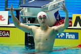 Sun Yang holds up four fingers on each hand above his head, in the swimming pool after the race.