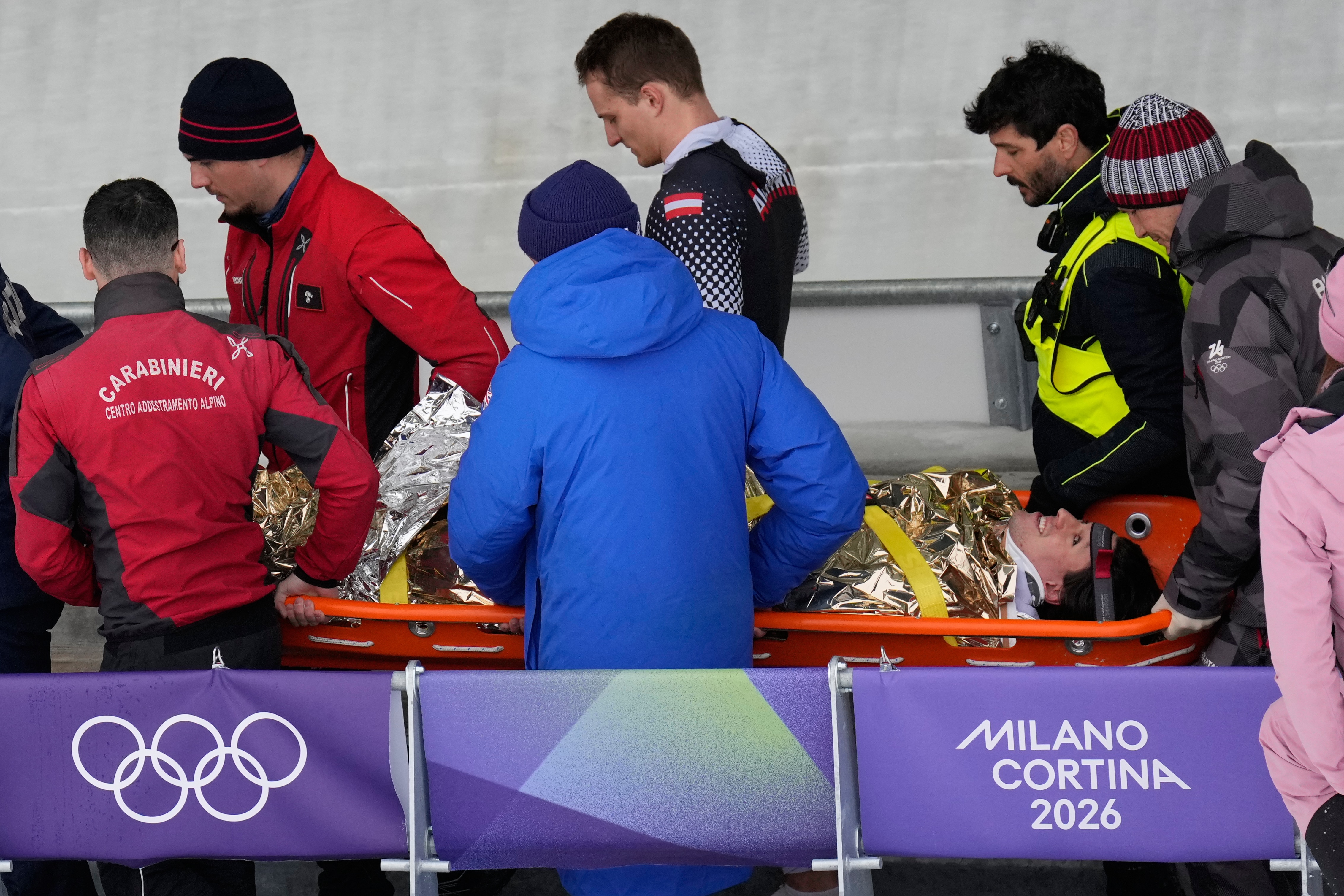 Jakob Manlbauer é levado em uma maca após cair durante evento olímpico de bobsleigh.