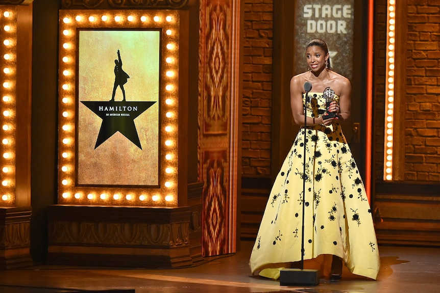 Actress in yellow dress holds award on stage