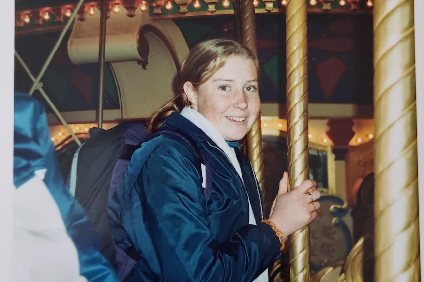 A smiling young woman on a carousel.