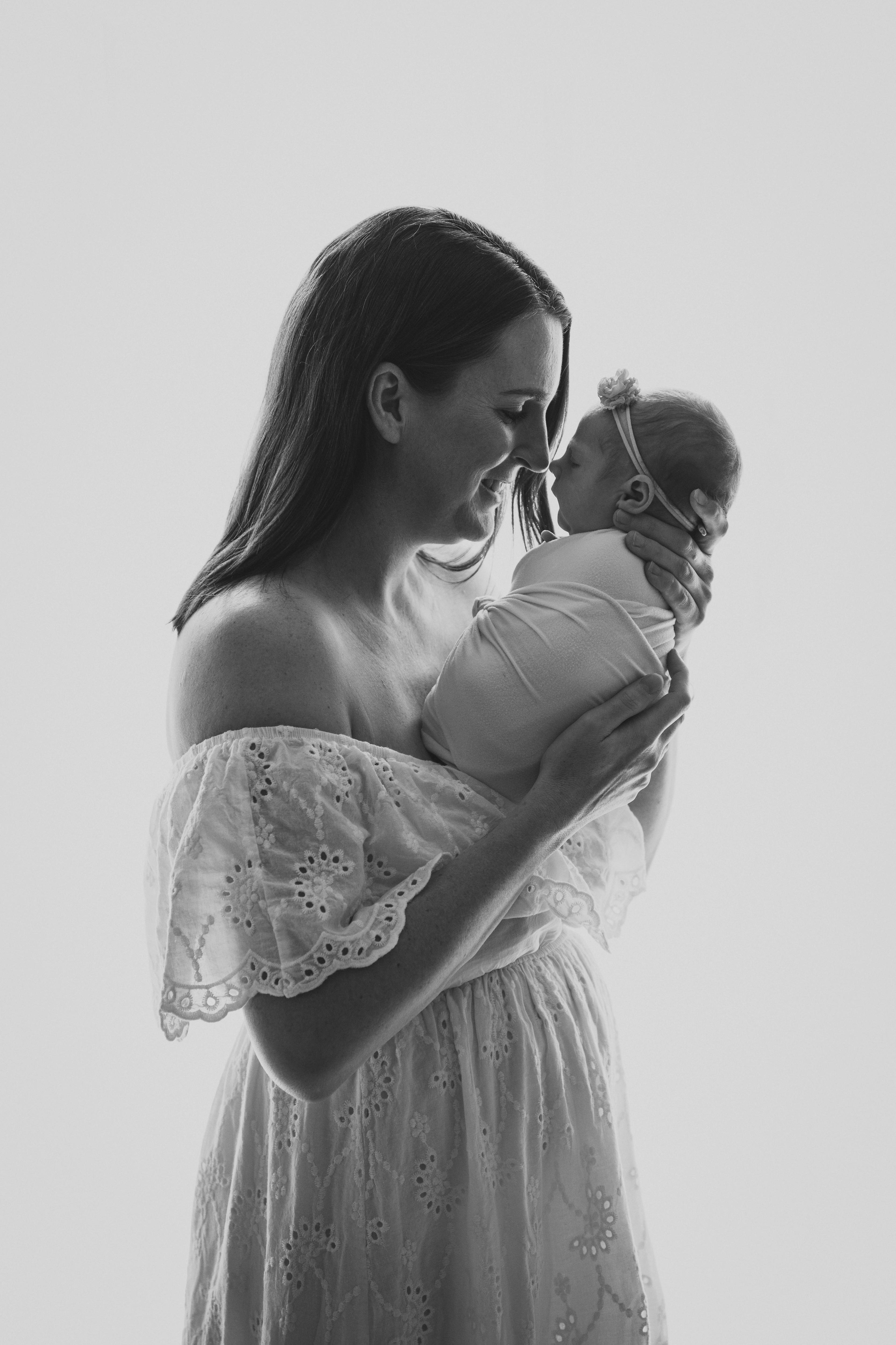 A black and white portrait of Lauren holding her baby daughter Daisy close to her face and smiling.