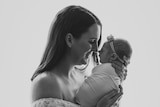 A black and white portrait of Lauren holding her baby daughter Daisy close to her face and smiling.