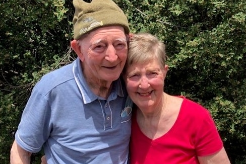 An old man and a woman pose for a photo together.