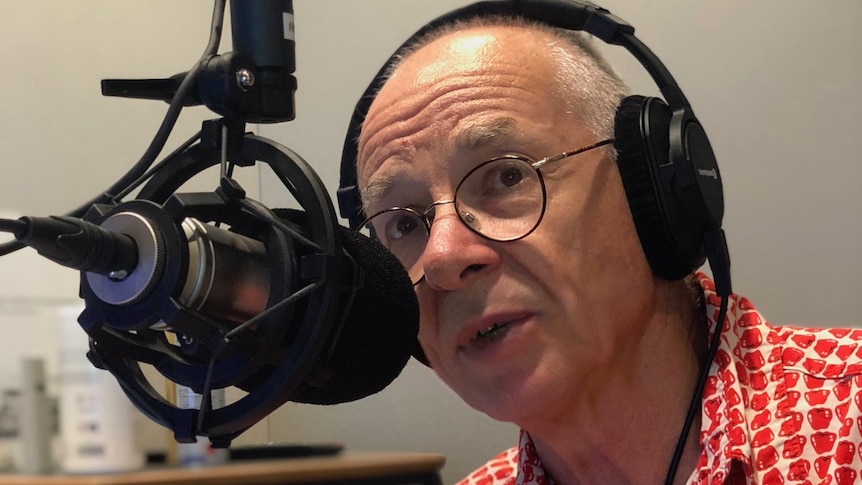 Man with headphones on talking into a microphone.