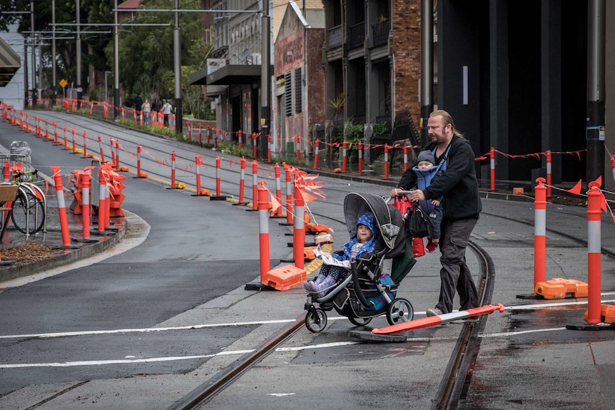 A man pushing a pram through a maze of orange markers