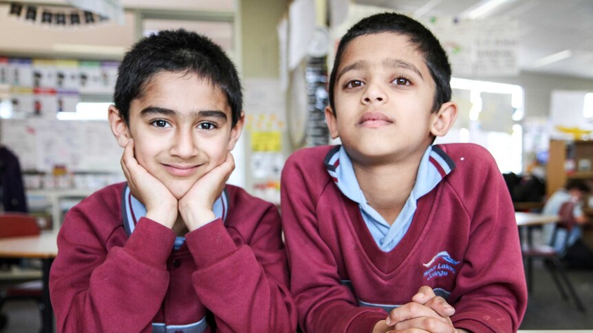 Year One students, Eesher and Atul sit at a classroom desk wearing school uniforms.