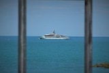 A cruise boat still at sea seen through two iron bars.