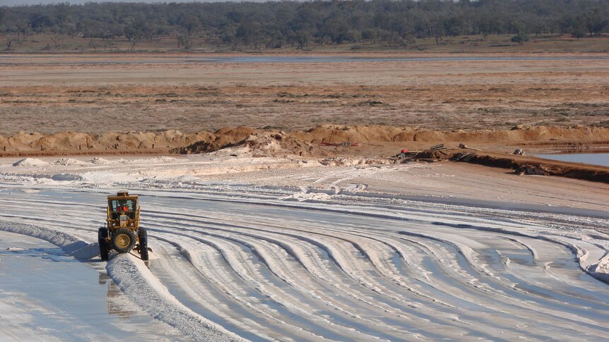 A tractor thins out the salt to help drying