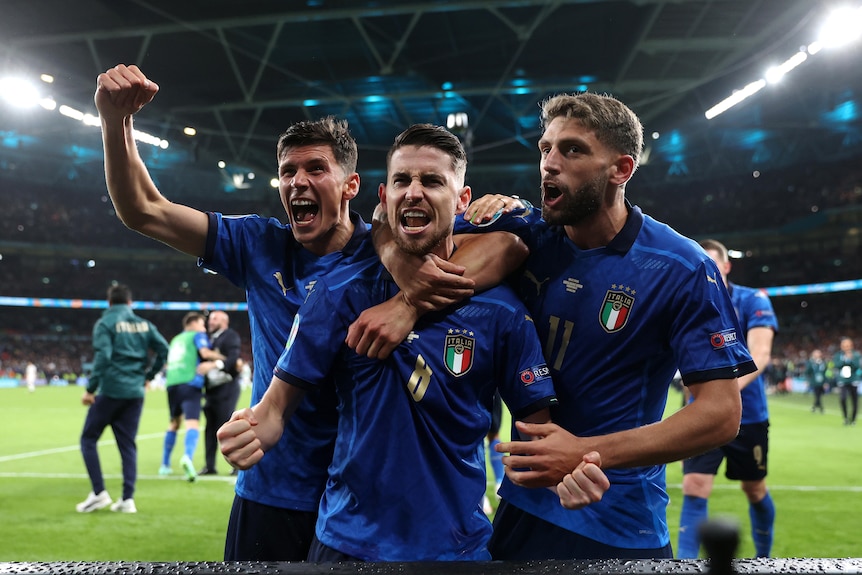 Trois footballeurs italiens s'embrassent et crient de joie alors qu'ils célèbrent le penalty gagnant lors d'une demi-finale de l'Euro 2020.