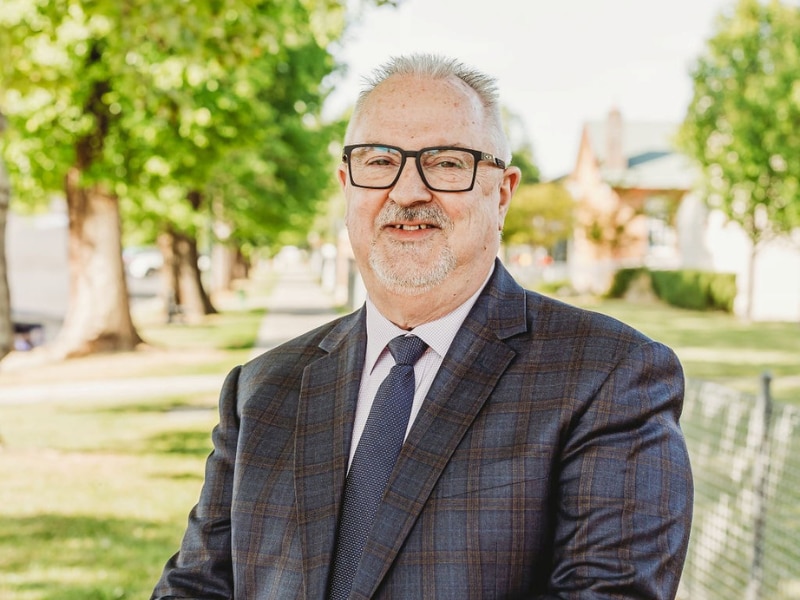 A man in a suit in a park alooking at the camera