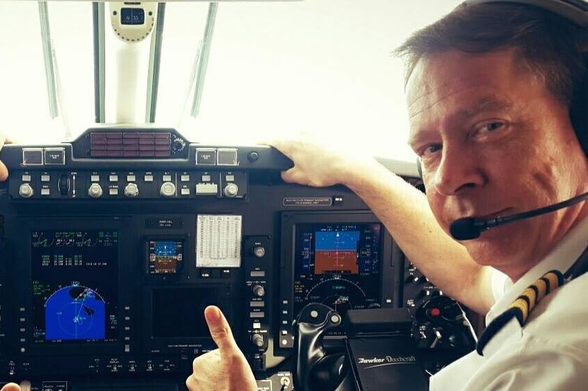 Two men look at the camera with an aeroplane flight deck behind them covered in buttons and dials