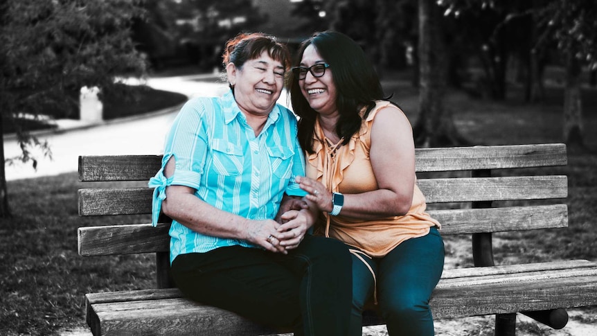 A woman and her elderly mum are pictured laughing on a park bench