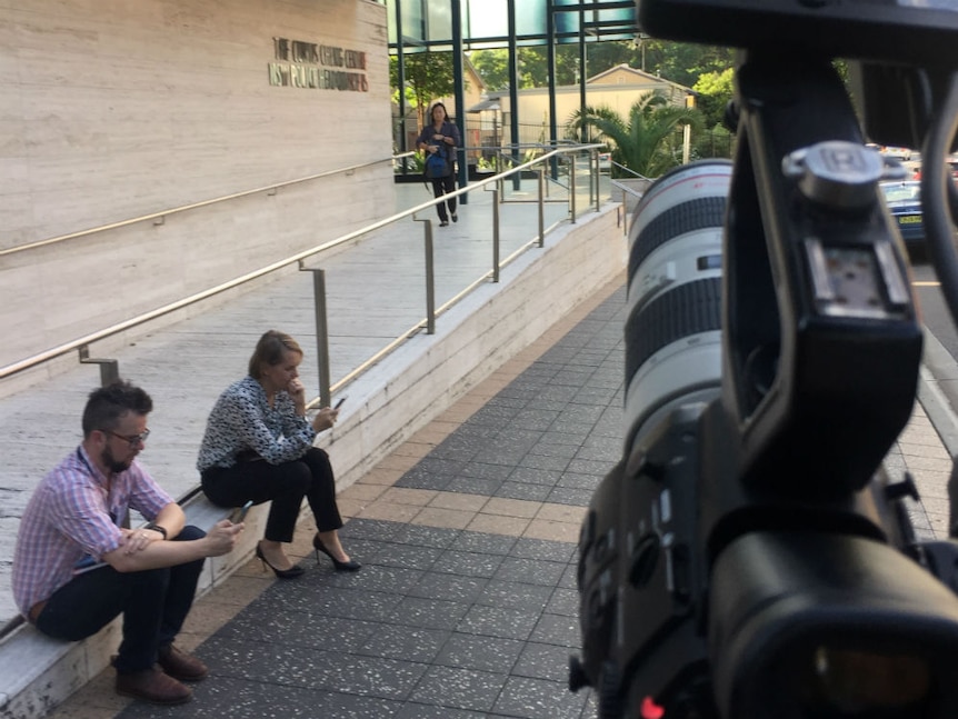 Justin Stevens and Sarah Ferguson sitting on the ground outside Parramatta police station during a break in filming The Siege.