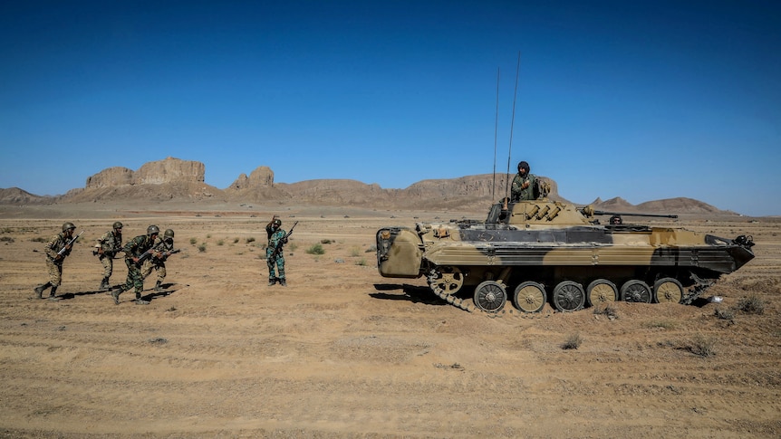 A tank and members of the Iranian Army take part in a military exercise in the desert of Isfahan.