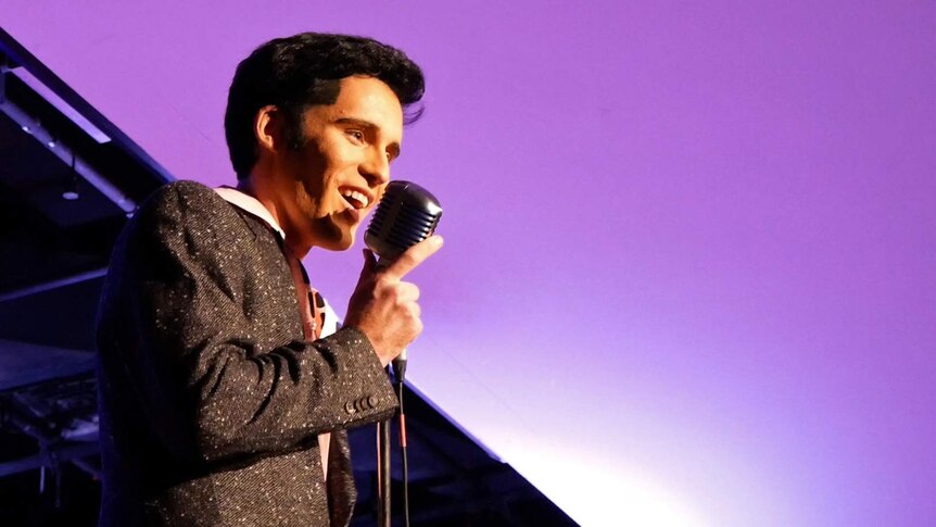 Elvis tribute artist Brody Finlay on stage he sings into an old fashioned microphone