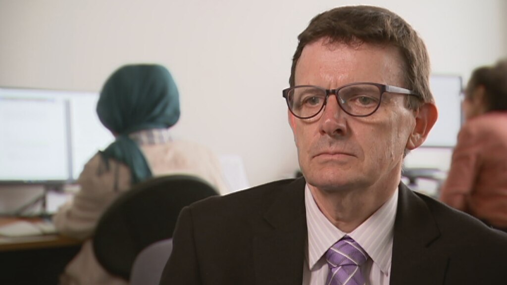 Headshot of Australian Refugee Council CEO Paul Power sits in an office.