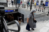 A nun wearing a face mask to prevent the spread of coronavirus climbs stairs of a subway.