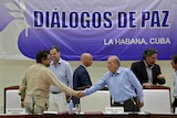 Colombia's lead government negotiator and Colombia's FARC lead negotiator shake hands.