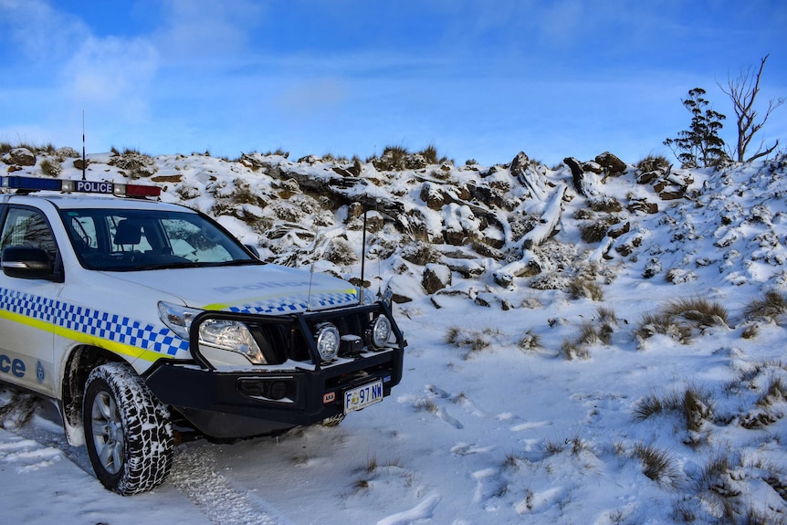A police car with a snowy landscape in the background.