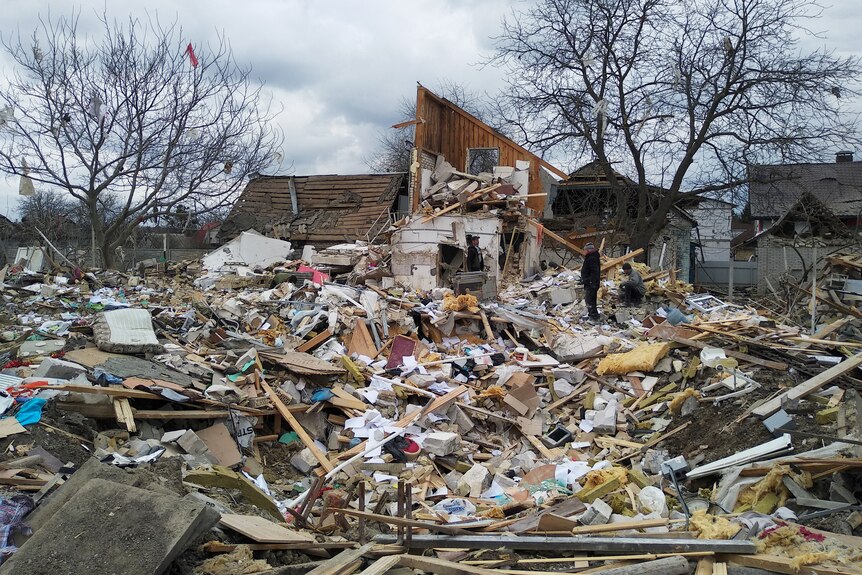 People amidst the debris of a house destroyed by shelling during Ukraine-Russia conflict