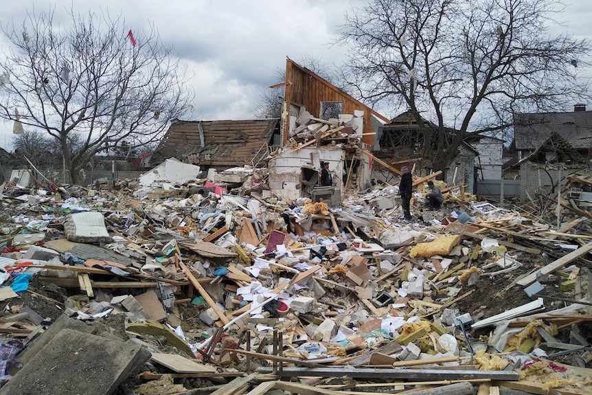 People amidst the debris of a house destroyed by shelling during Ukraine-Russia conflict