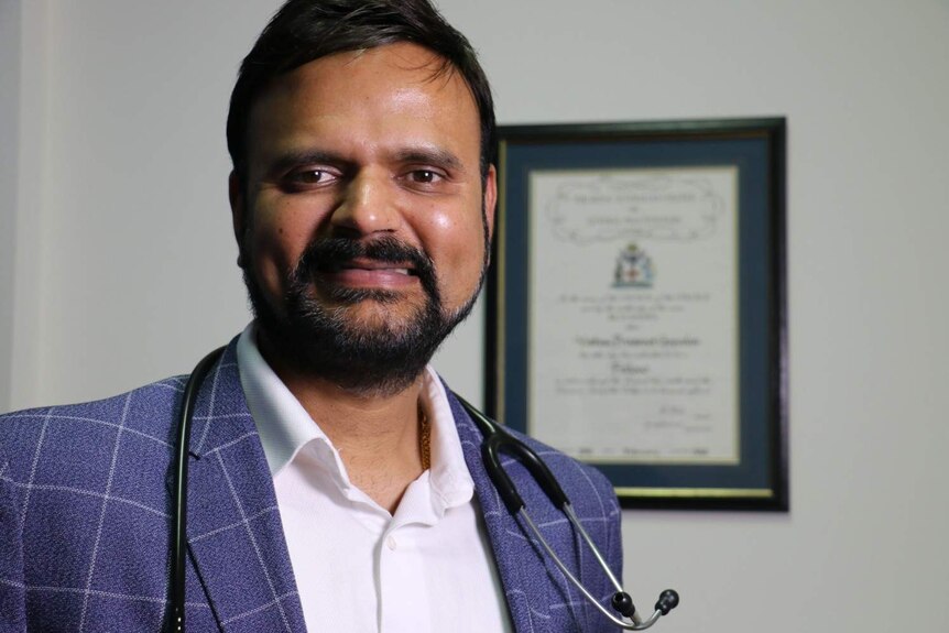 A close up of Dr Vishnu Gopalan with a stethoscope around his neck in a blue checked blazer.