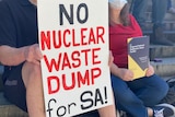 A close up of a sign with back and red words saying: No nuclear waste dump in SA