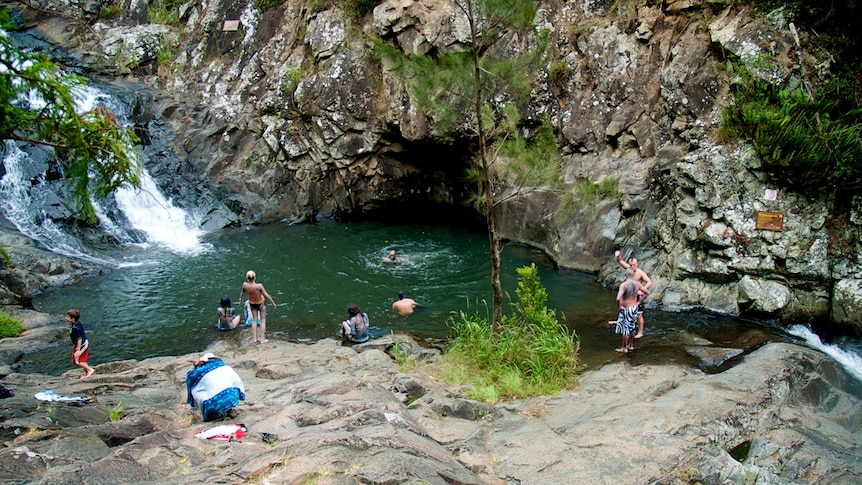 Swimmers at a hinterland waterfall and waterhole.