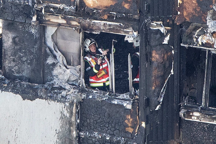 A fireman seen inside a window of the blackened tower.