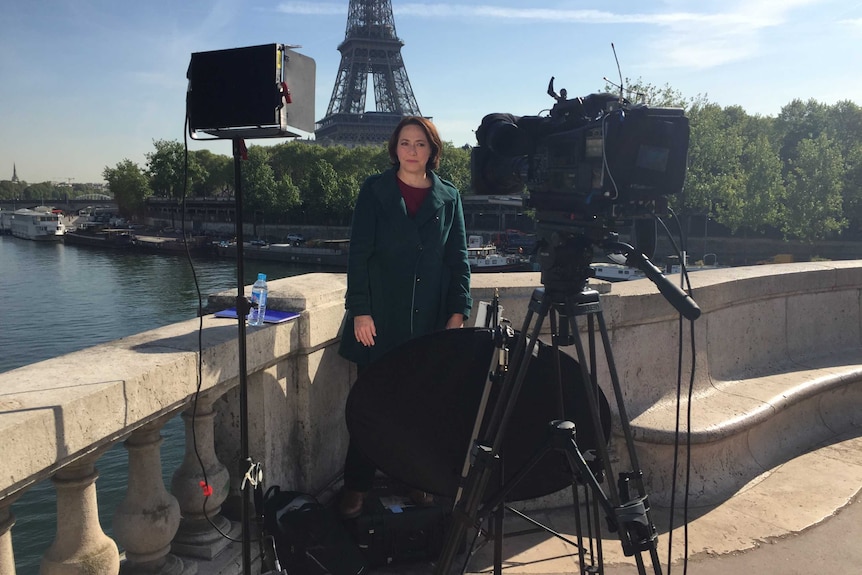 Millar standing in front of tower surrounded by light, camera, bounce board.