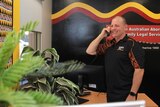 A photo of Steve Smith standing in the office of the Aboriginal Investment Group, talking on the phone.
