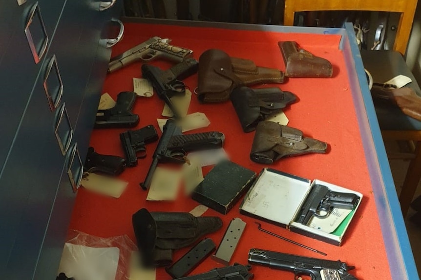 A drawer filled with pistols, magazines and holsters.