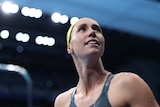 Hero shot of a swimmer with her cap on looking up to the crowd at the Olympics 