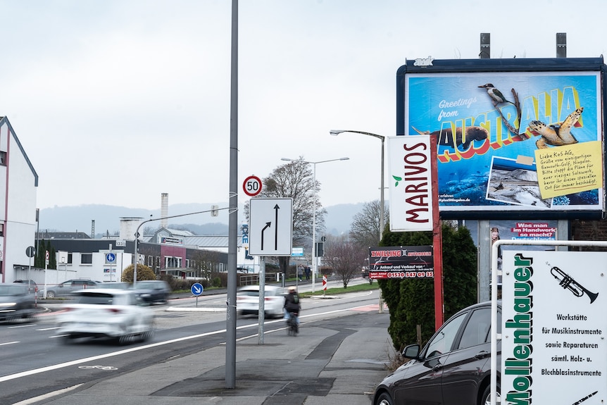 На ярком рекламном щите в стиле открытки изображены дюгонь, морская черепаха и птица, а также фотография соляного завода.