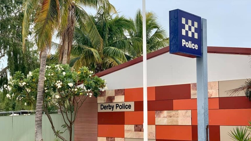 An outback police station with palm trees around it.