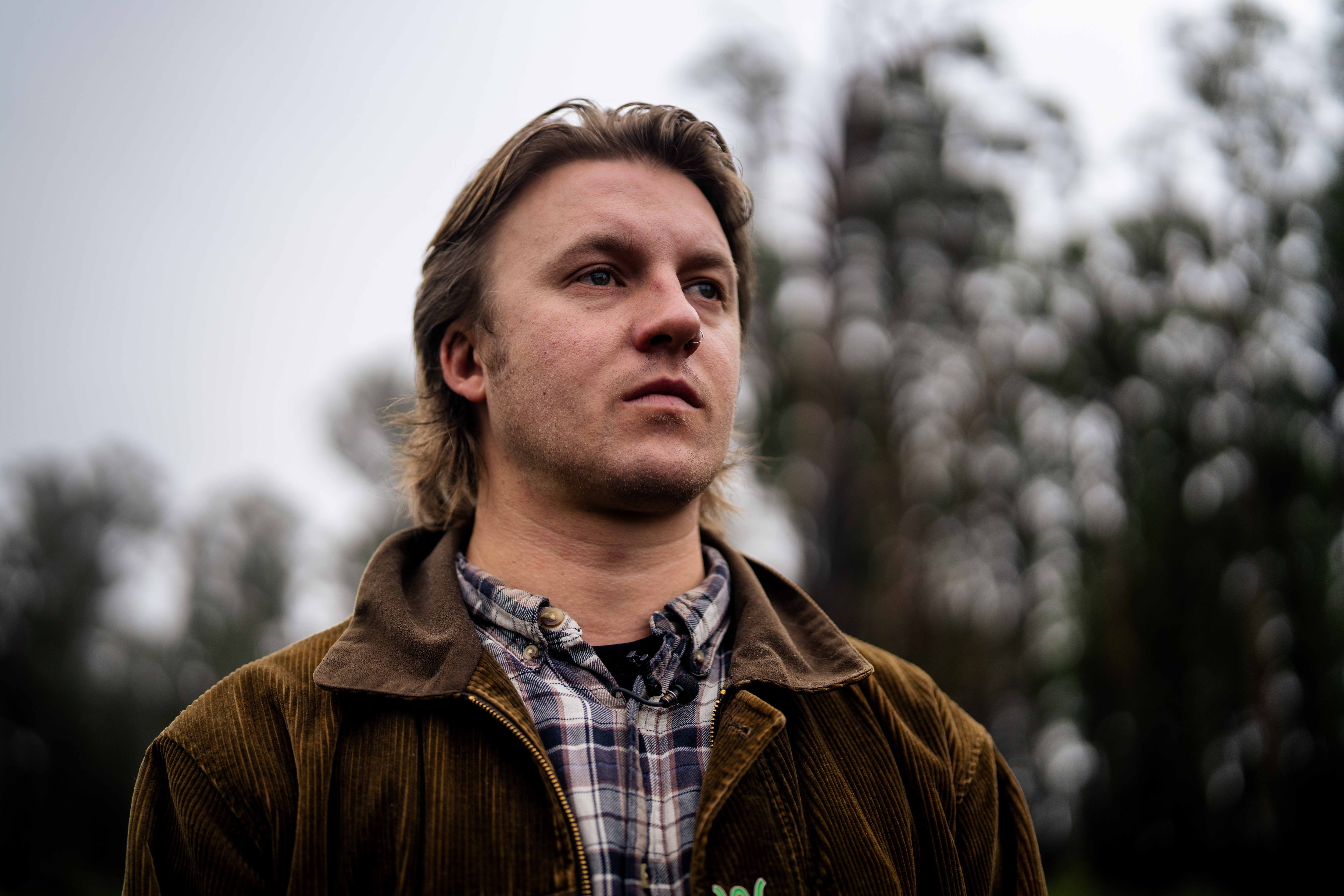 A young man looks out to the distance amongst trees